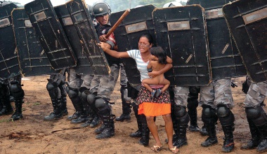10 Mar 2008, Brazil --- March 10, 2008 - Lagoa Azul 2, Amazonas, Brazil - Amazon indian tribe called Sater-mau battle local police over a land disbute. Five months pregnant indian , Mani Sater, 21, tries to stop troops, from removing her people with her one year old on her hip. The advance of Amazonas state policemen who were expelling the woman and from a privately-owned tract of land on the outskirts of Manaus, in the heart of the Brazilian Amazon. Her husband and 400 other tribe members are squatting on a rural sector between the cities of Itacoatiara and north of Manaus in the state of Amazonas. An group of local natives the Satere took over a property illegally, which is owned by a Japanese citizen who asked the police to intervene in removing the natives from his property. The landless peasants tried in vain to resist the eviction with bows and arrows against police using tear gas | Location: Lagoa Azul 2, Amazonas, Brazil. --- Image by © Luiz Vasconcelos/ZUMA Press/Corbis